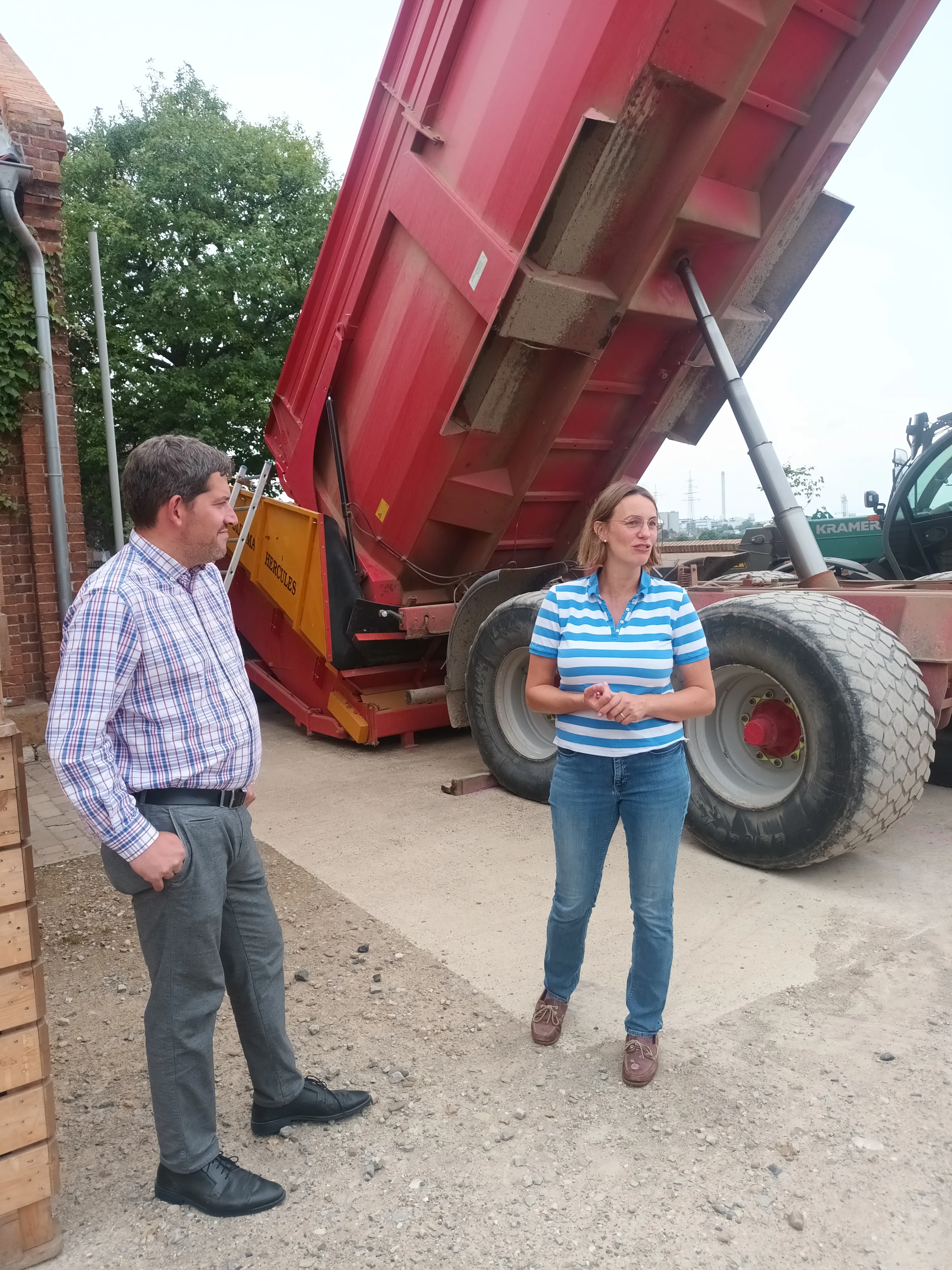 Kai Dräger und Henrike Bauermeister-Mund vor dem Anhänger während der Erläuterung des Ernteprozesses