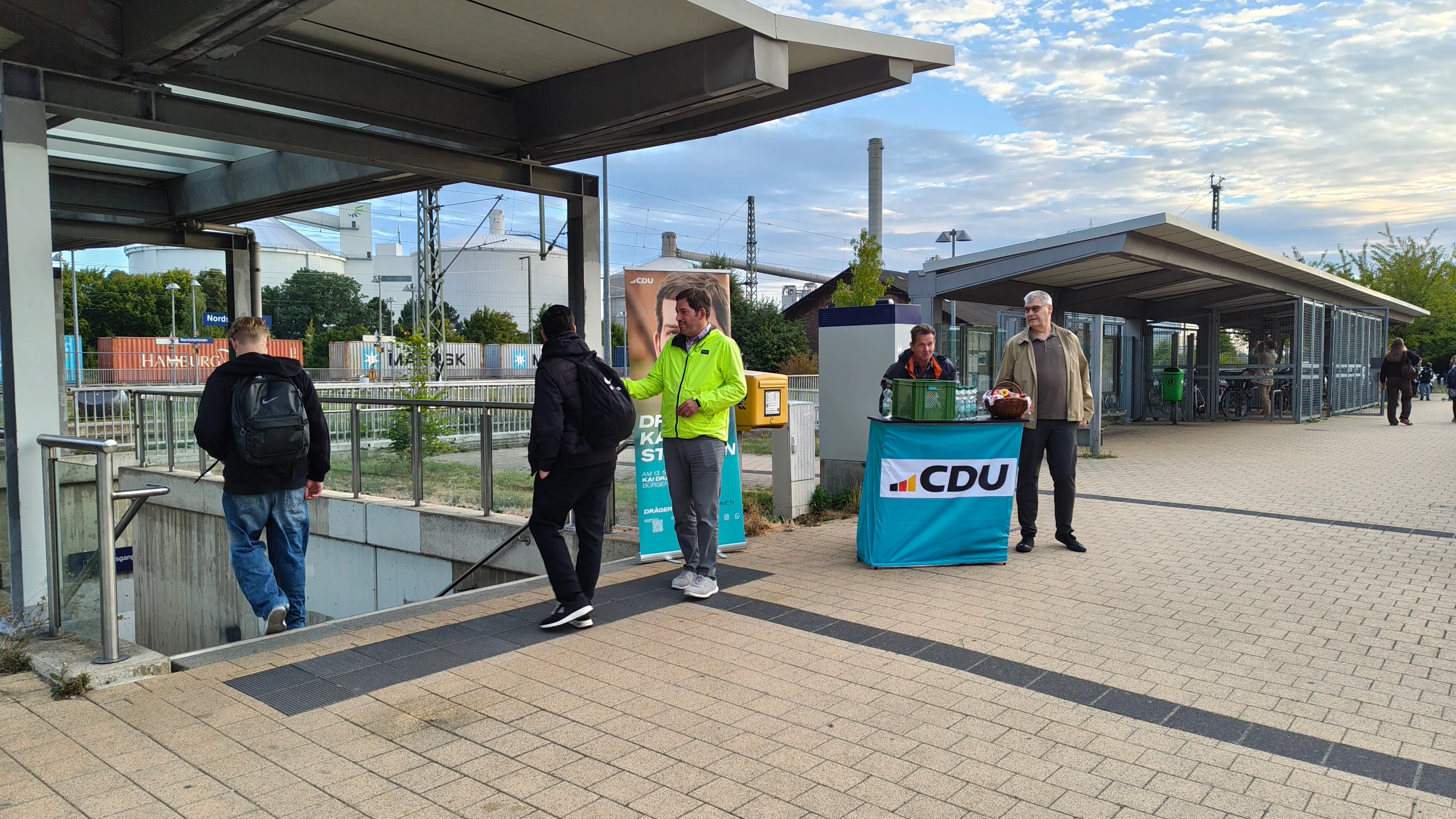 Bürgermeisterkandidat Kai Dräger (l.) im Gespräch mit einem Pendler am Bahnhof Nordstemmen. Im Hintergrund der Infostand mit Frühstückstüten für die Pendlerinnen und Pendler.